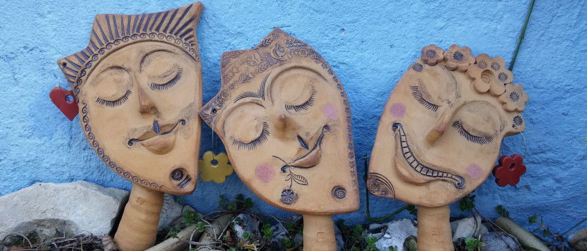 Drei aus Keramik gestaltete Gesichter als Blumentopfstecker
